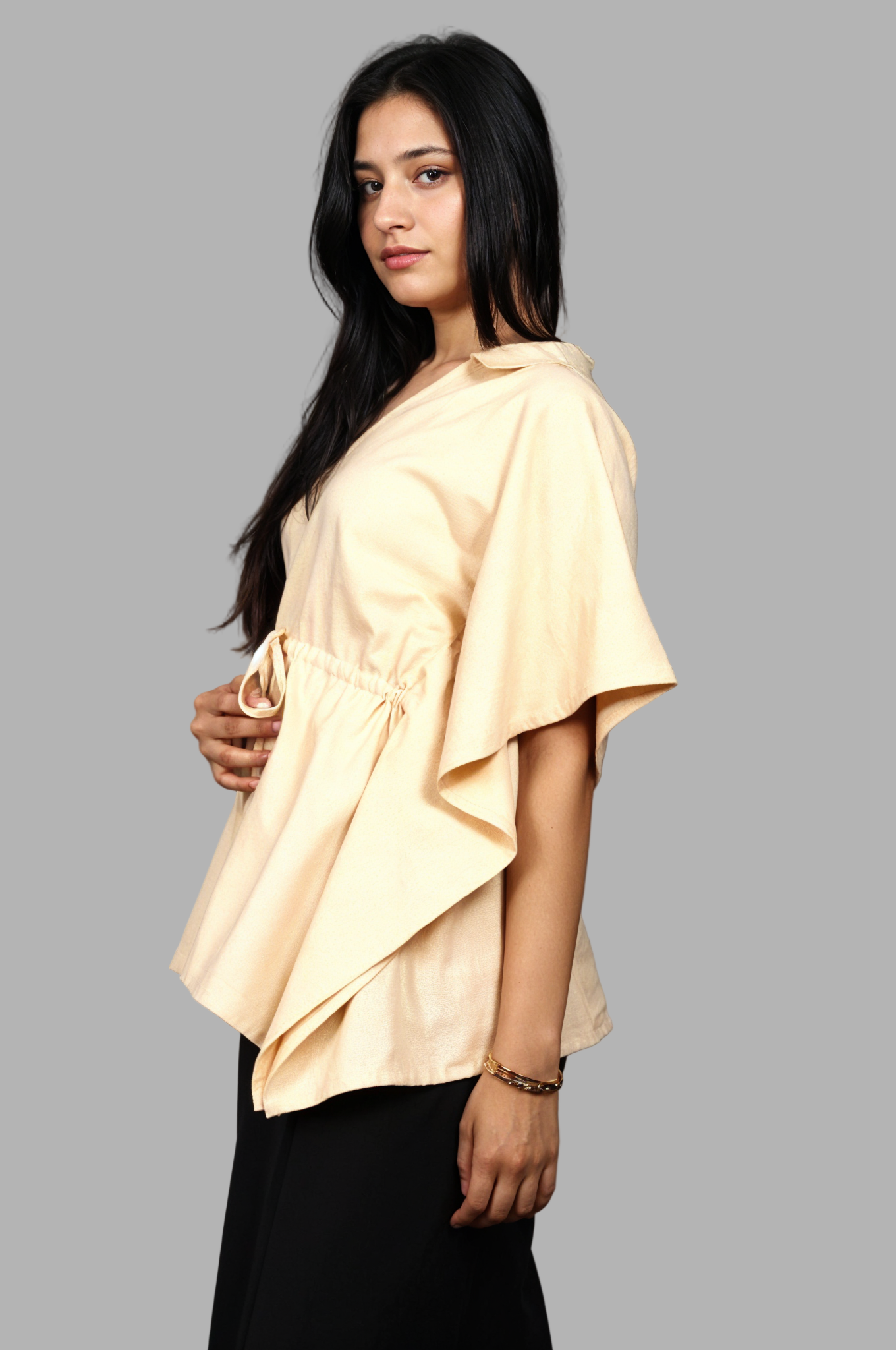 Woman wearing a fullblank branded beige kaftan called AIRA-A with a plain background