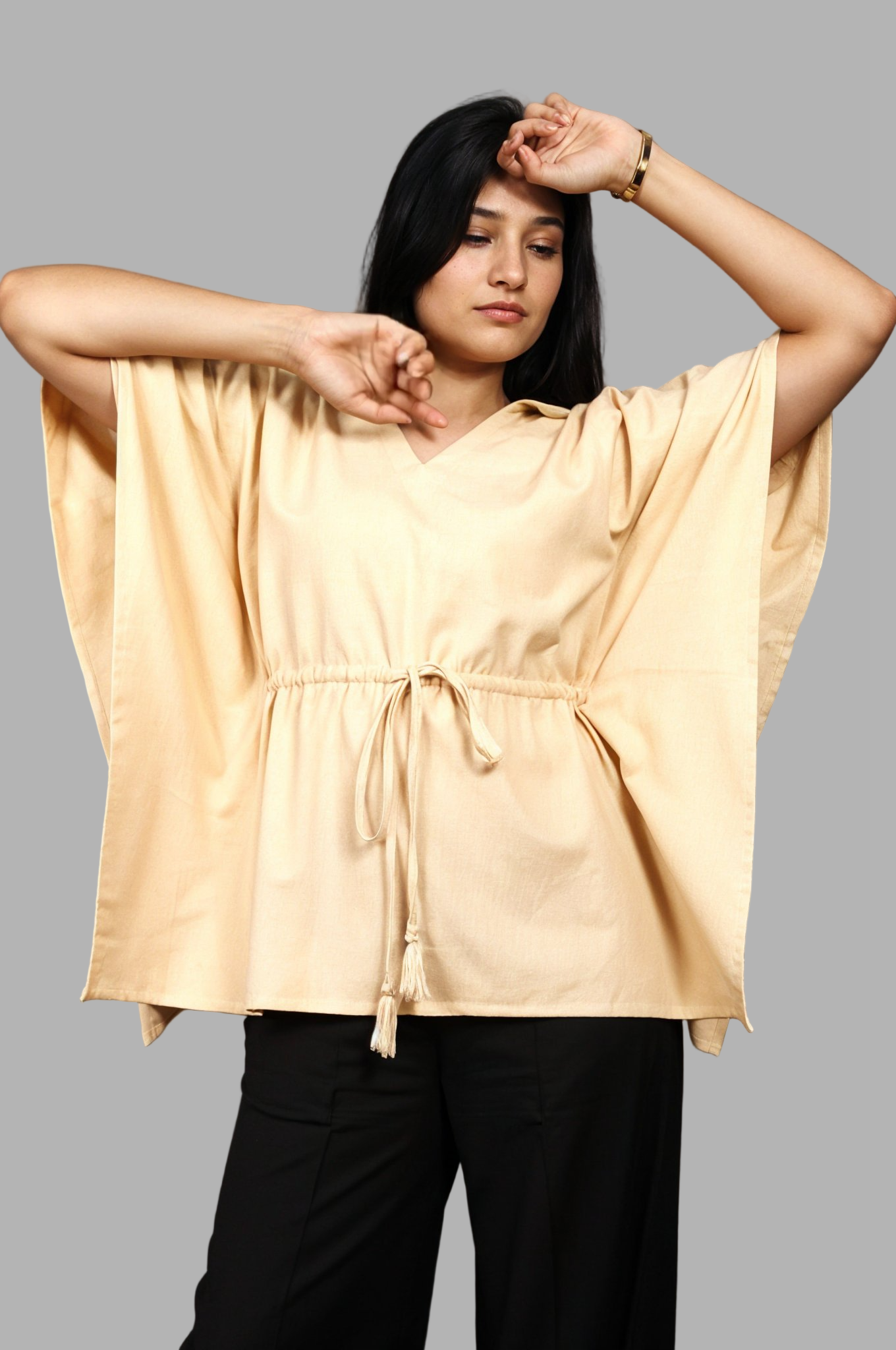Woman wearing a fullblank branded beige kaftan called AIRA-A with a plain background
