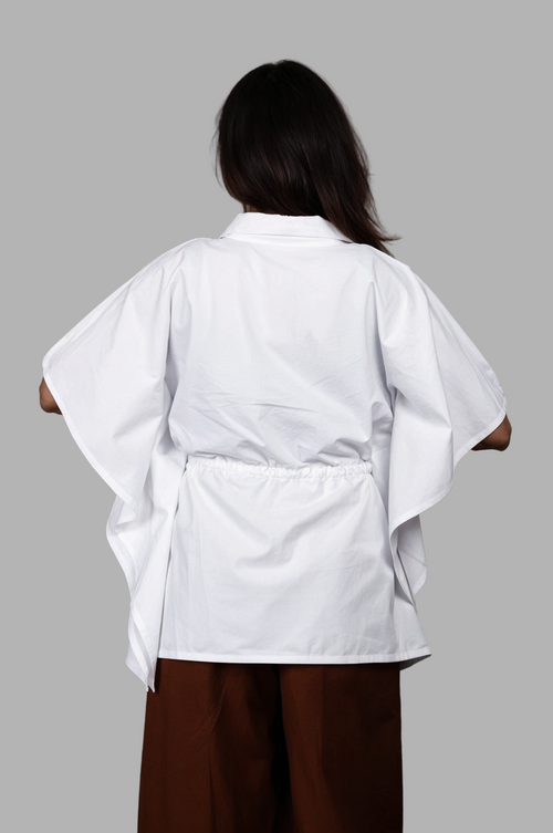 Woman wearing a fullblank branded white kaftan called AIRA-B with a plain background