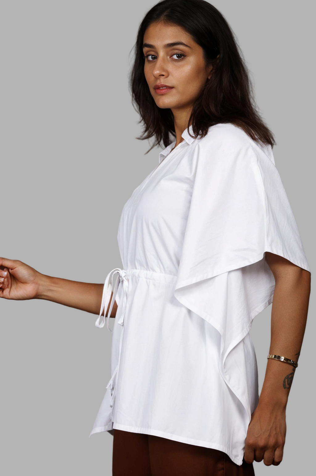 Woman wearing a fullblank branded white kaftan called AIRA-B with a plain background