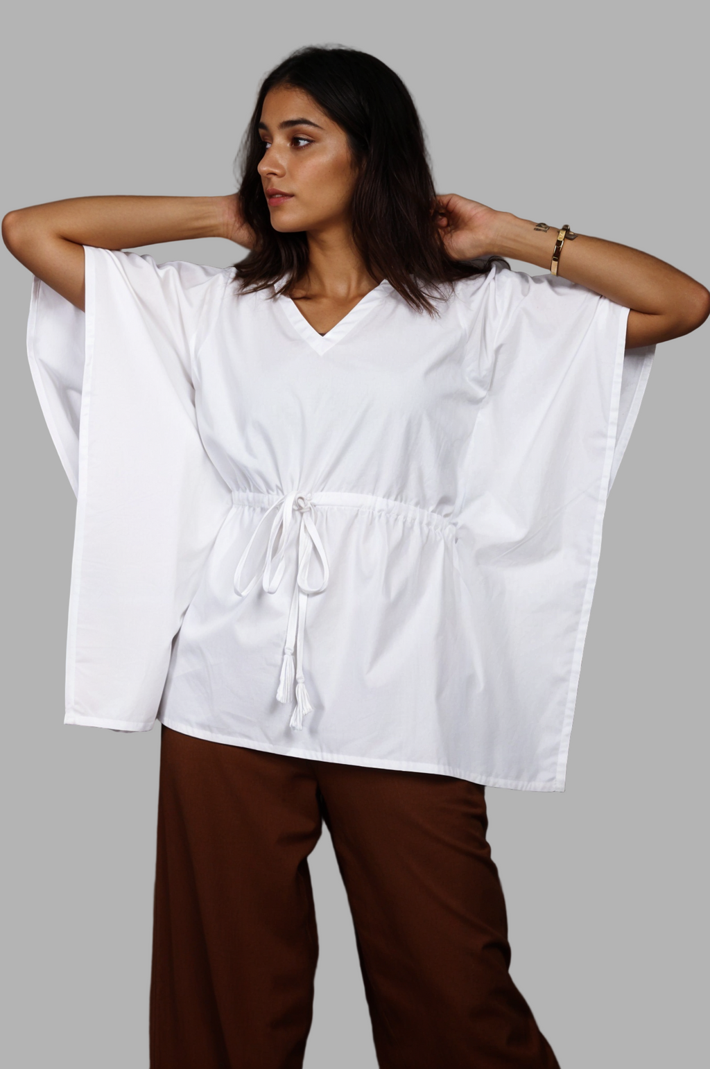 Woman wearing a fullblank branded white kaftan called AIRA-B with a plain background