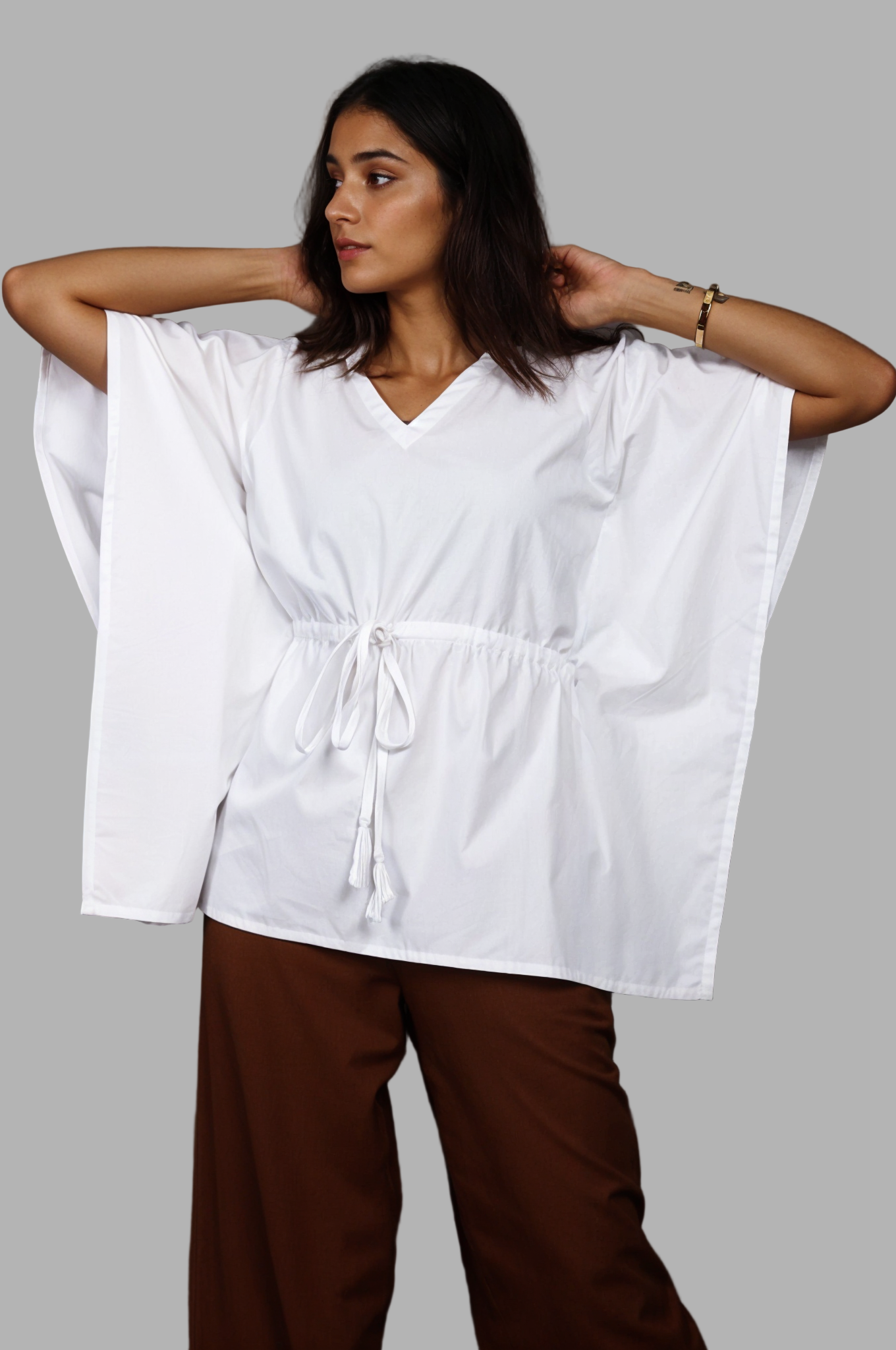 Woman wearing a fullblank branded white kaftan called AIRA-B with a plain background