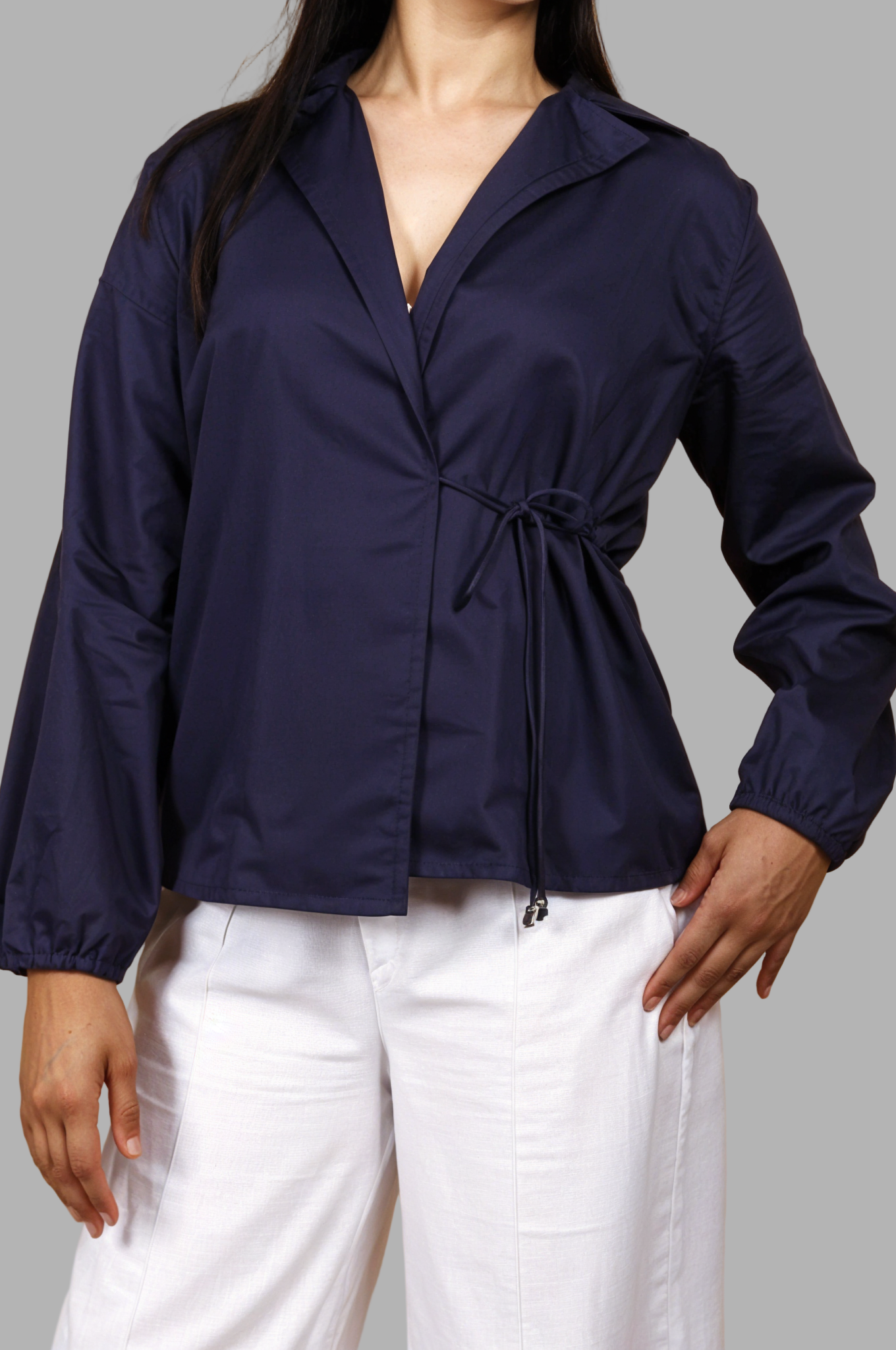 Woman wearing a fullblank branded navy blue shirt called CLEO-B with a tie detail on a plain background