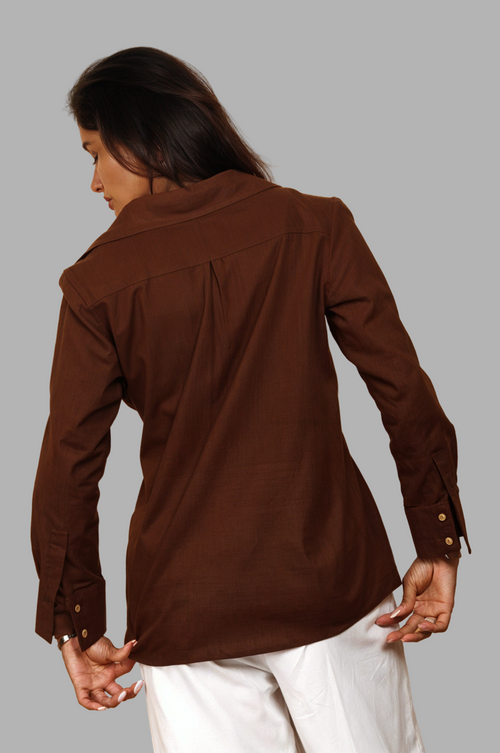 Woman wearing a fullblank branded brown shirt called COCO-A with a plain background