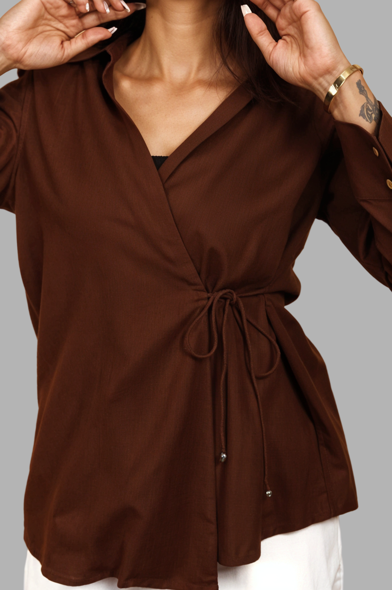 Woman wearing a fullblank branded brown shirt called COCO-A with a plain background