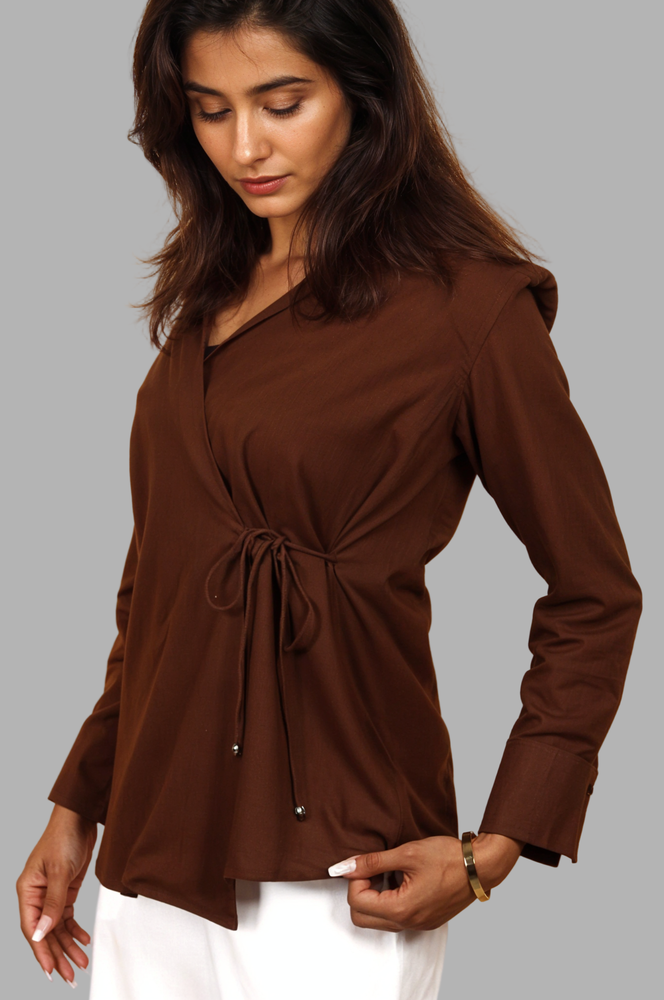 Woman wearing a fullblank branded brown shirt called COCO-A with a plain background