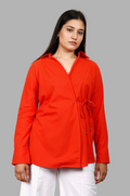 Woman wearing a fullblank branded red orange shirt called COCO-B on a plain background