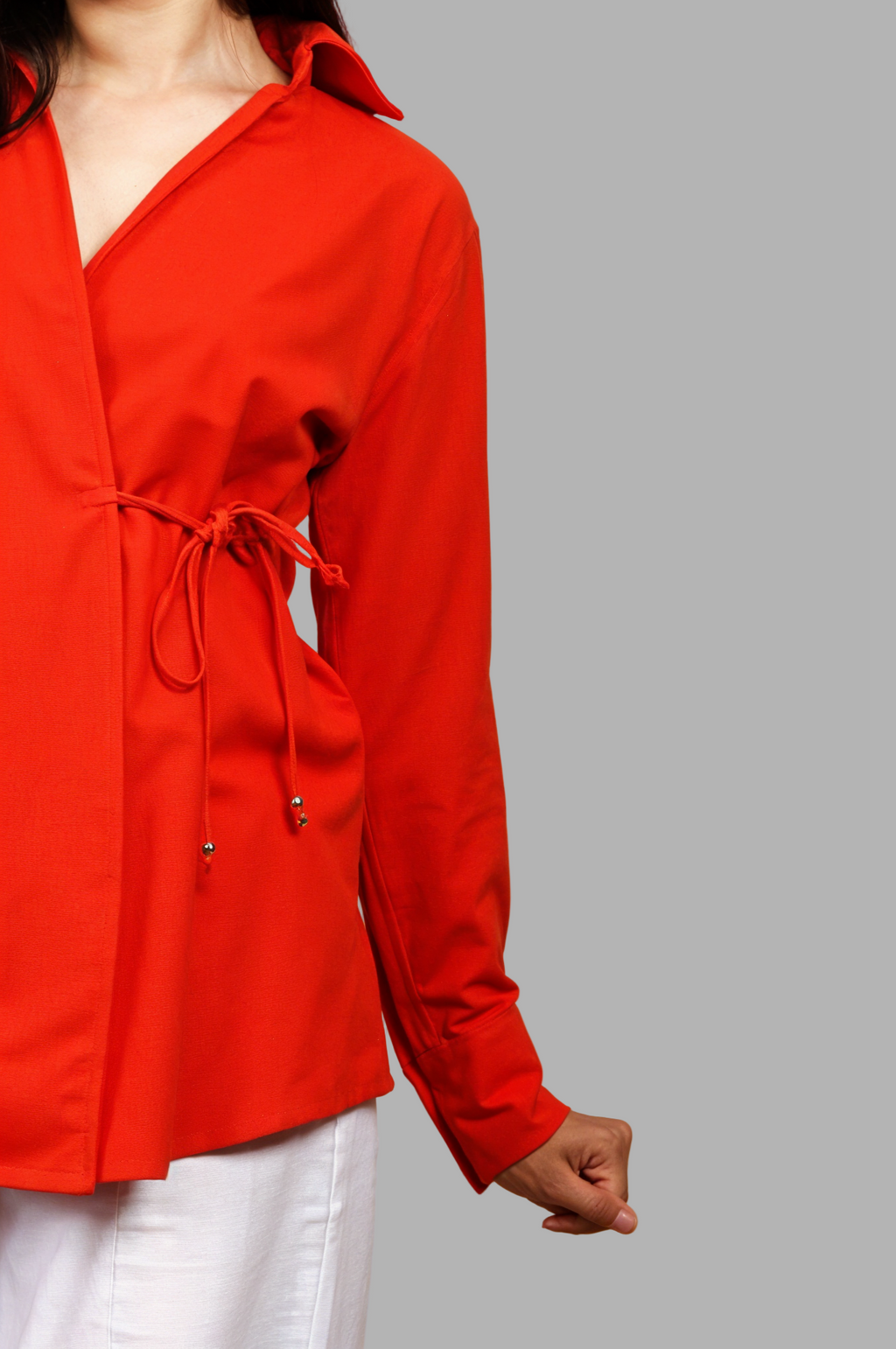 Woman wearing a fullblank branded red orange shirt called COCO-B on a plain background