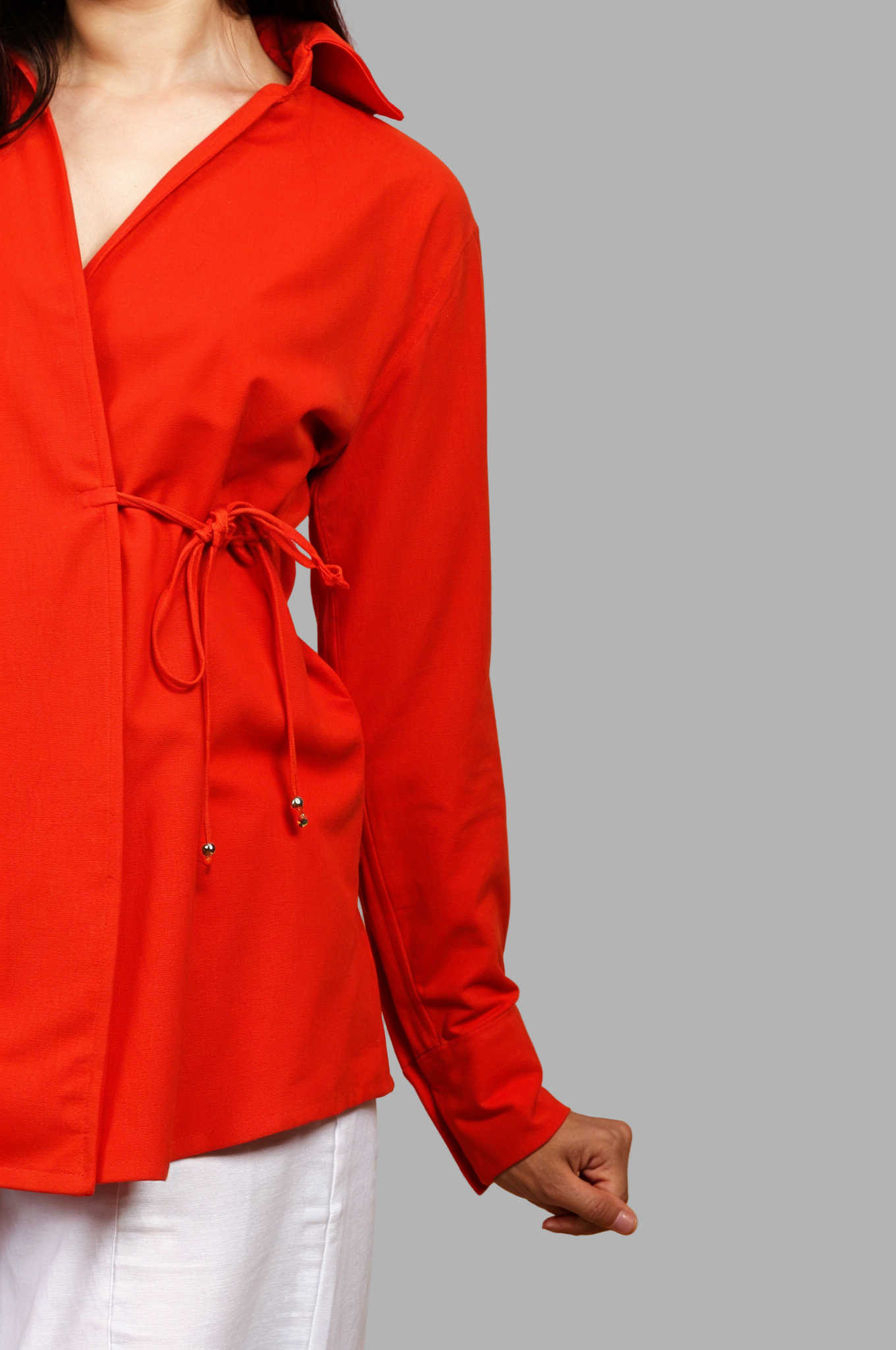 Woman wearing a fullblank branded red orange shirt called COCO-B on a plain background