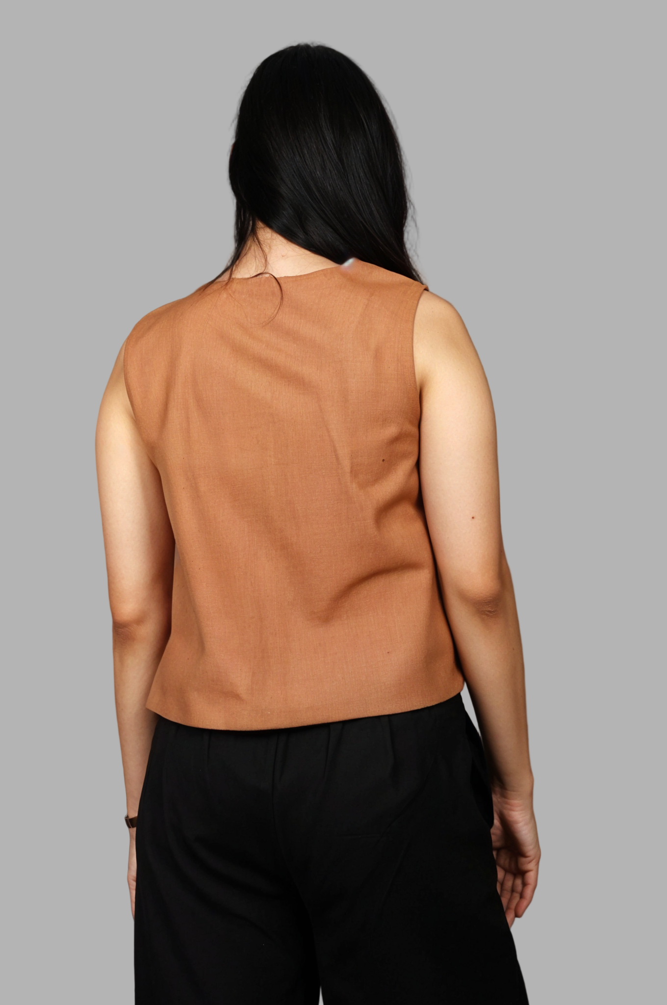 Woman wearing a fullblank branded brown sleeveless top called EIRA-A with a plain background