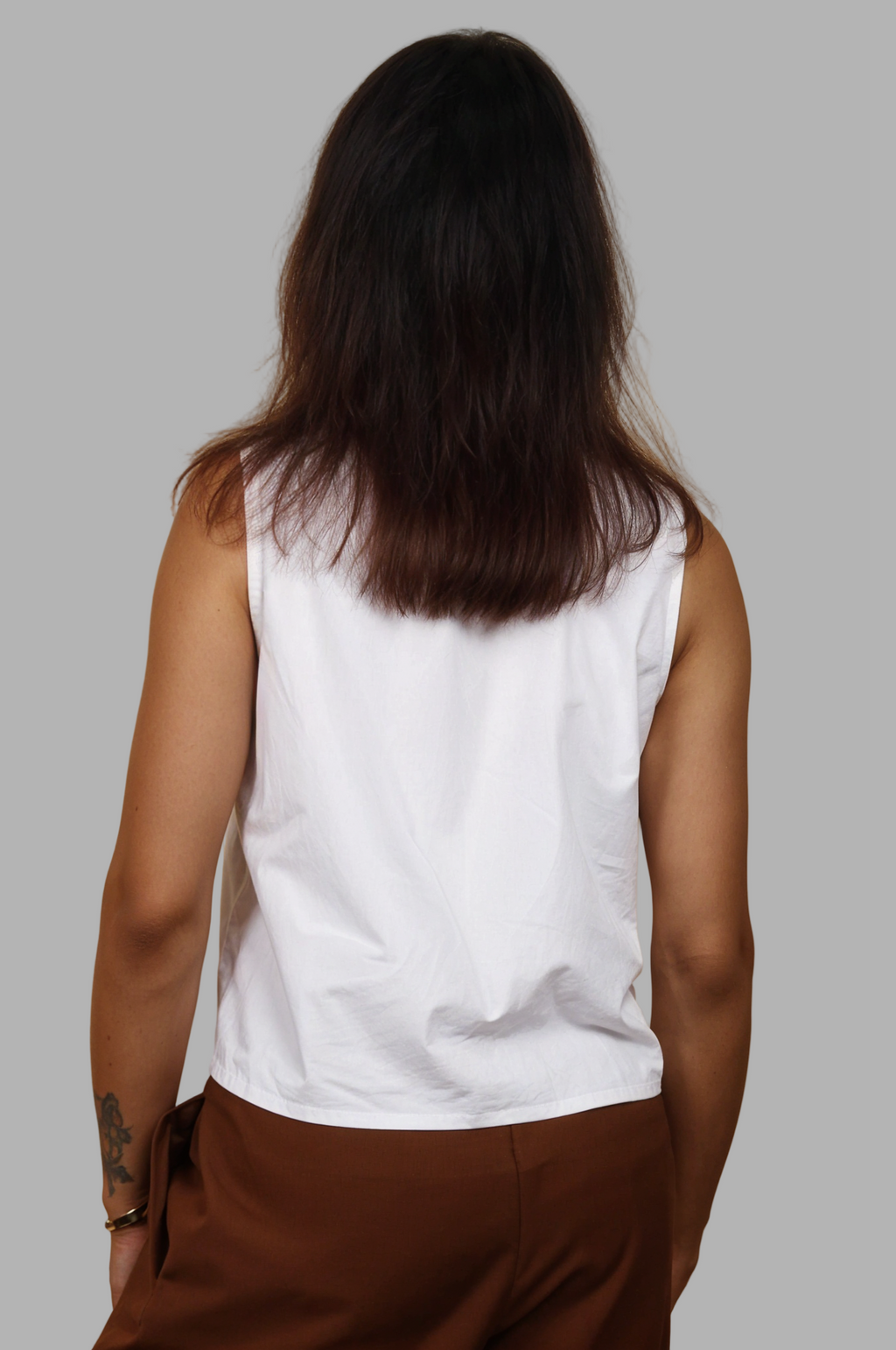 Woman wearing a fullblank branded white sleeveless top called KIKI-A with a plain background