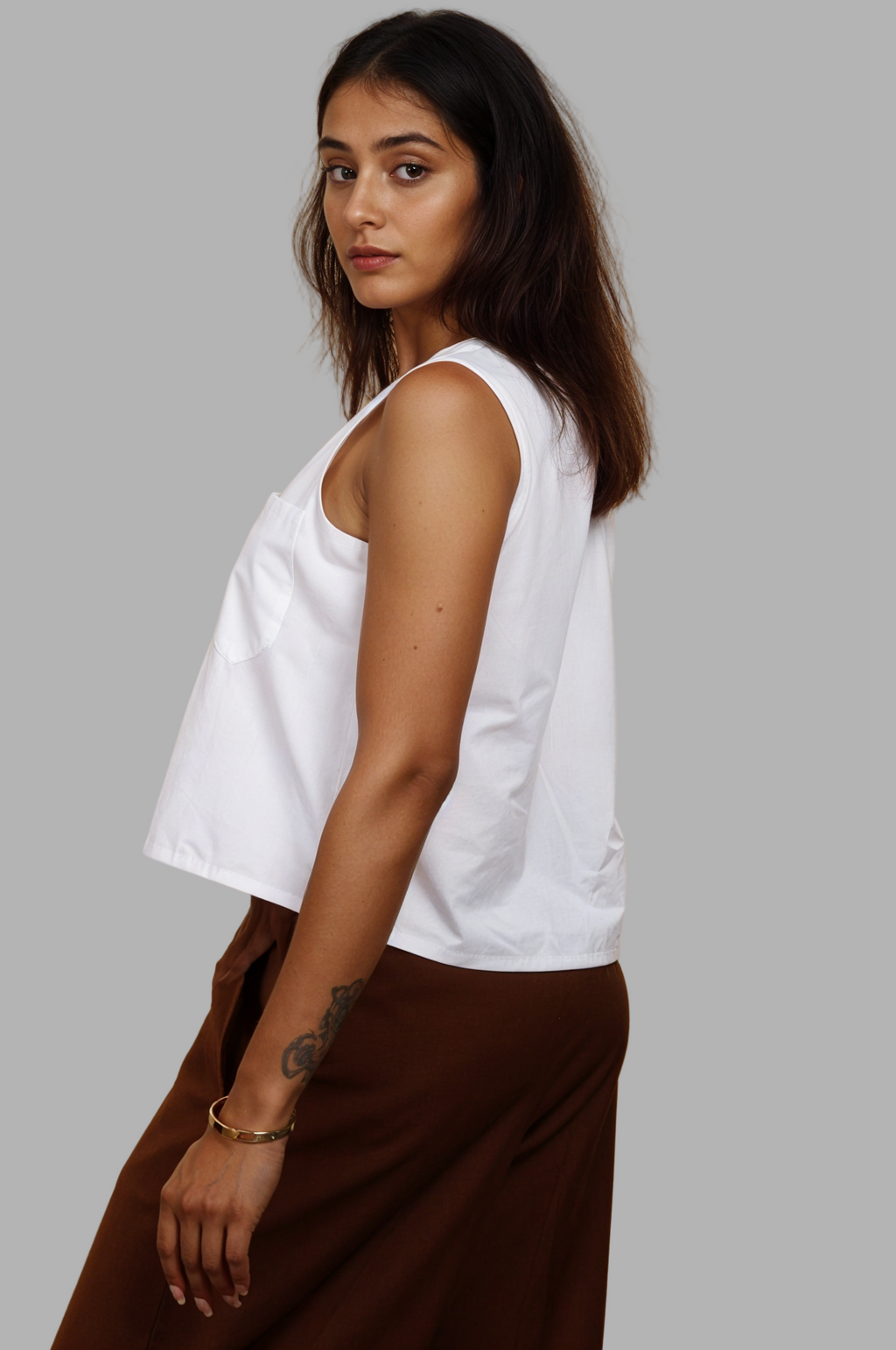 Woman wearing a fullblank branded white sleeveless top called KIKI-A with a plain background