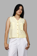 Woman wearing a fullblank branded light yellow sleeveless top called KIKI-B with a plain background