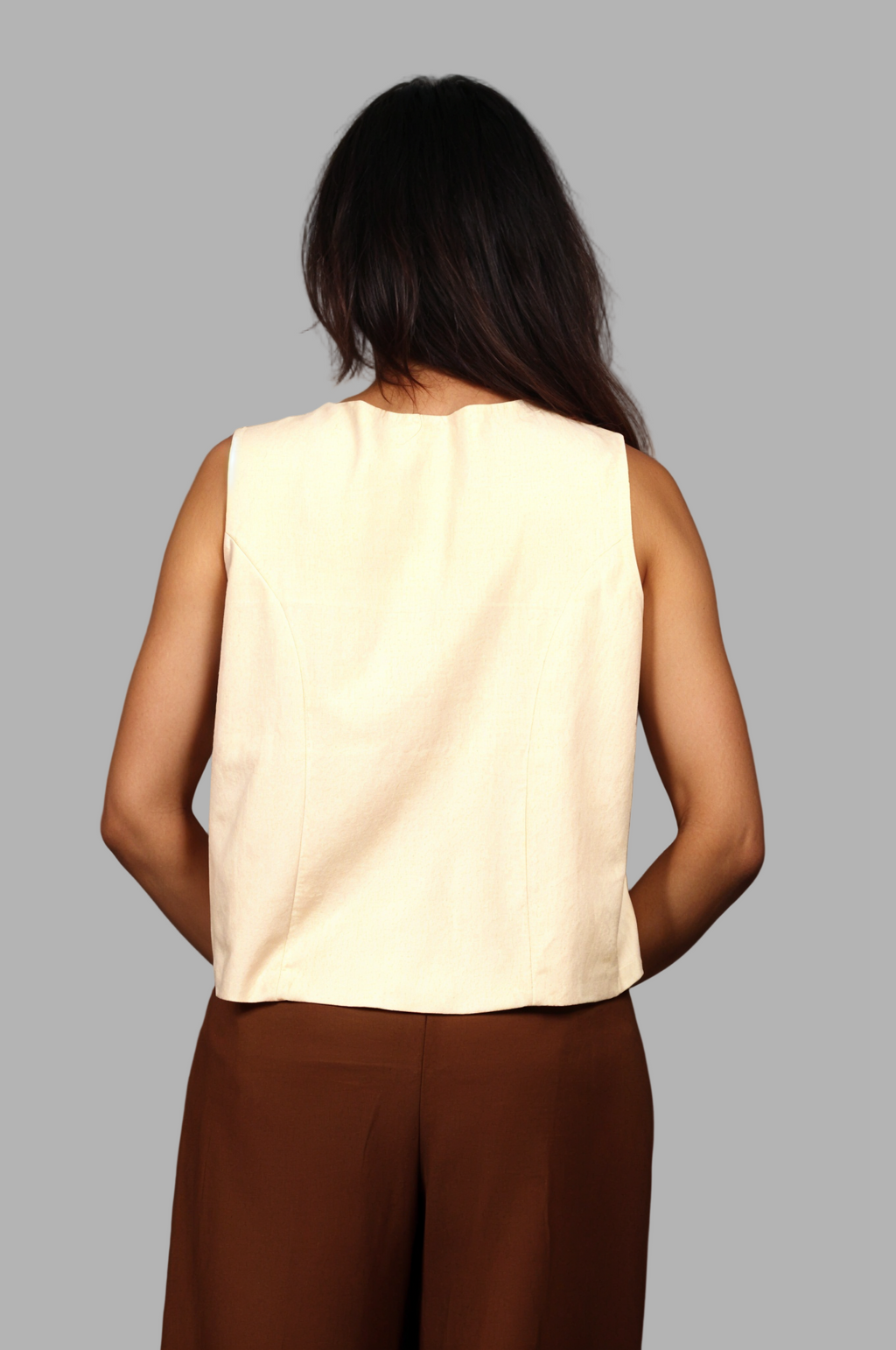 Woman wearing a fullblank branded beige vest called KIRA-B with a plain background