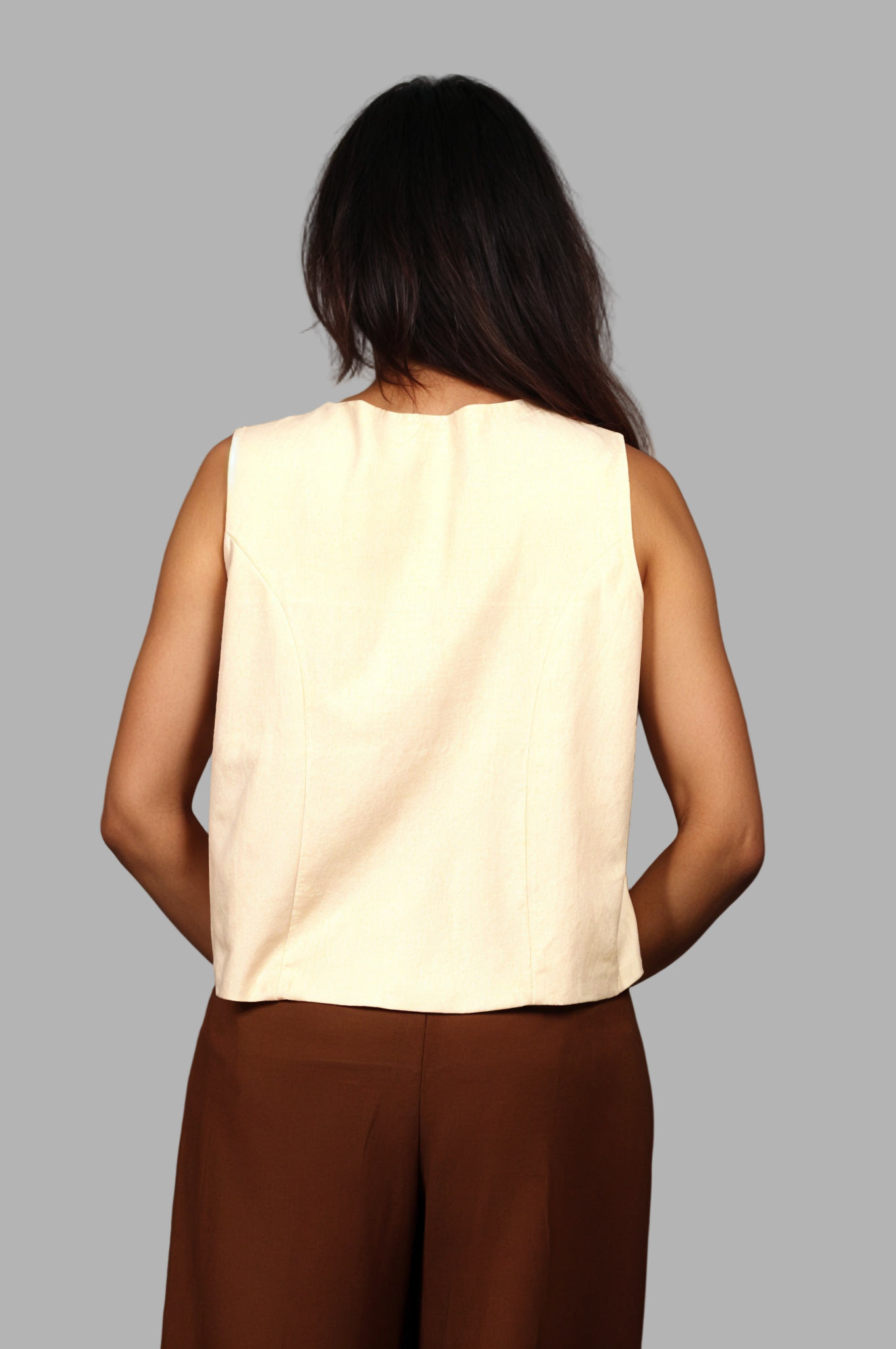 Woman wearing a fullblank branded beige vest called KIRA-B with a plain background