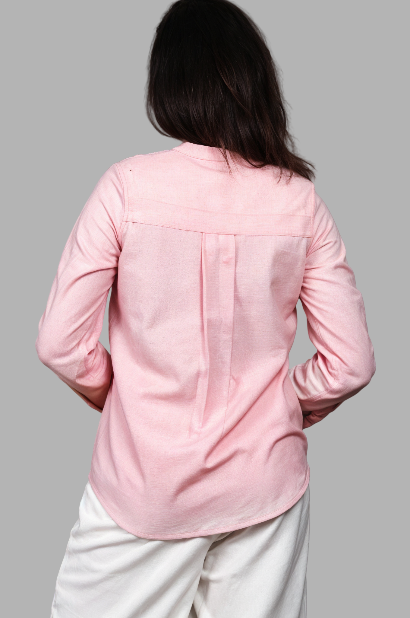 Woman wearing a fullblank branded pink full-sleeves shirt called ORA-A with a plain background