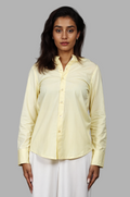 Woman wearing a fullblank branded light yellow full-sleeves shirt called ORA-B with a plain background