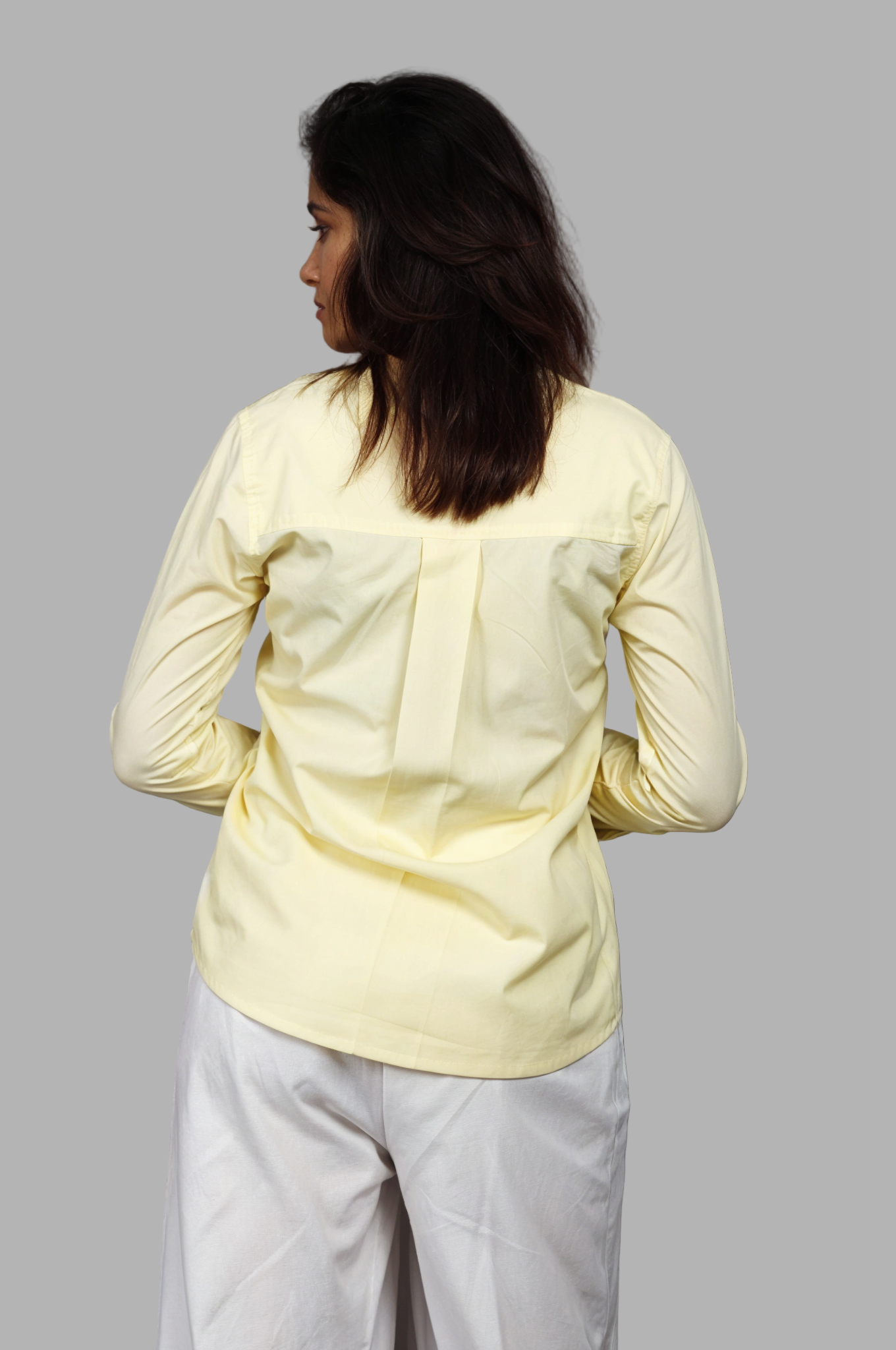 Woman wearing a fullblank branded light yellow full-sleeves shirt called ORA-B with a plain background