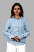 Woman wearing a fullblank branded light blue shirt called PEARL-B with a plain background