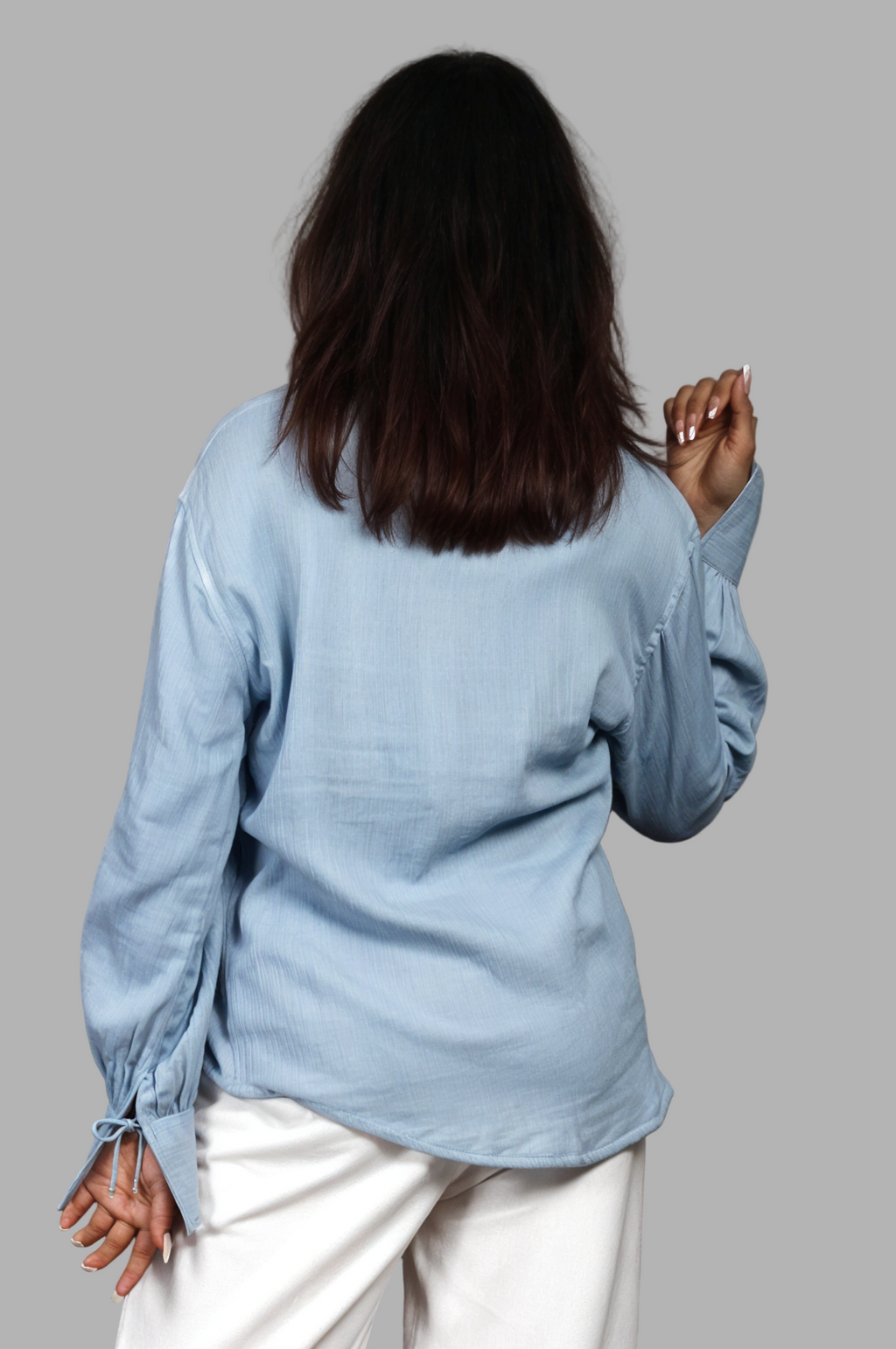 Woman wearing a fullblank branded light blue shirt called PEARL-B with a plain background