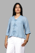 Woman wearing a fullblank branded light blue top called RIVA-B with a plain background