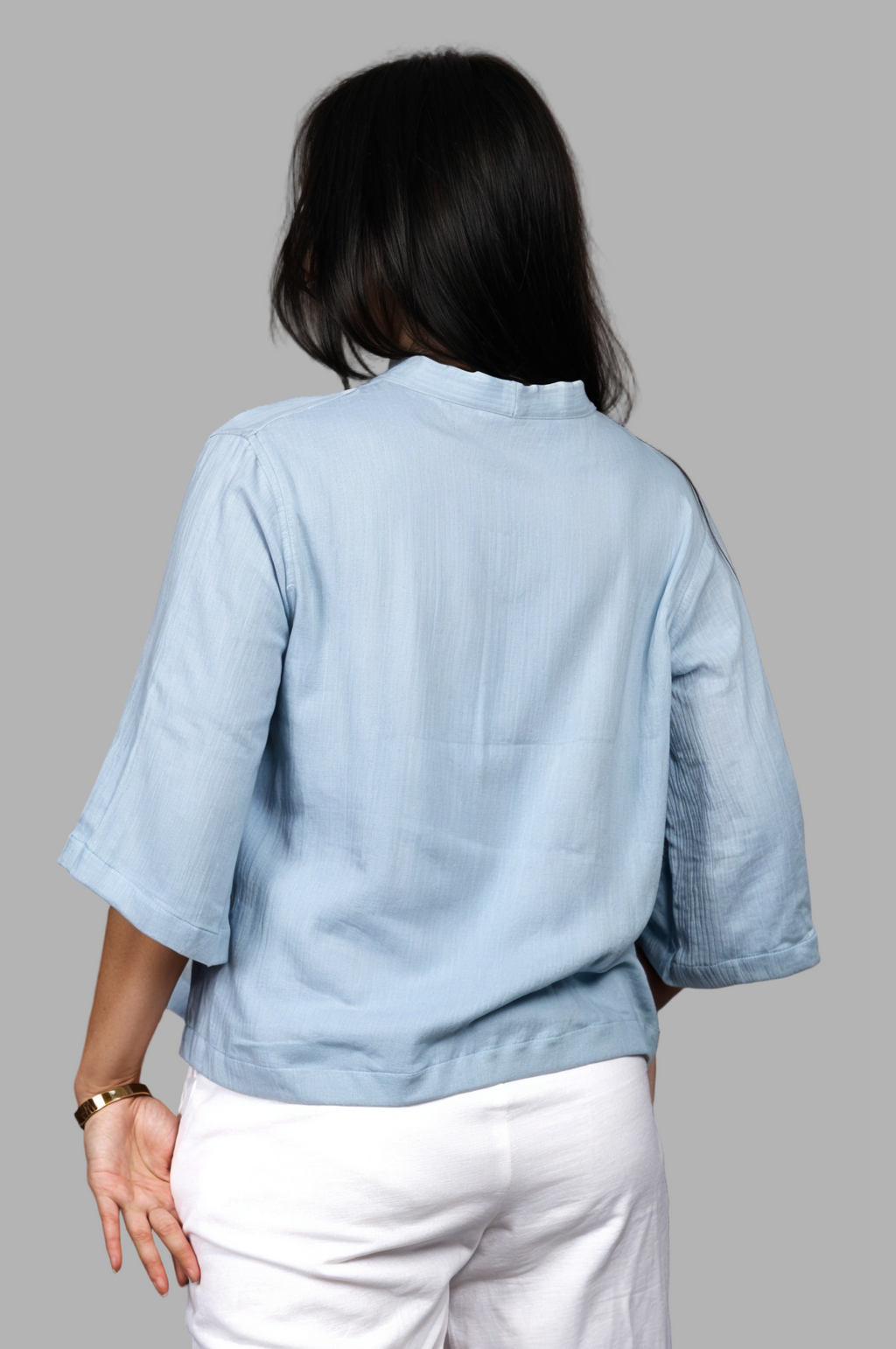 Woman wearing a fullblank branded light blue top called RIVA-B with a plain background