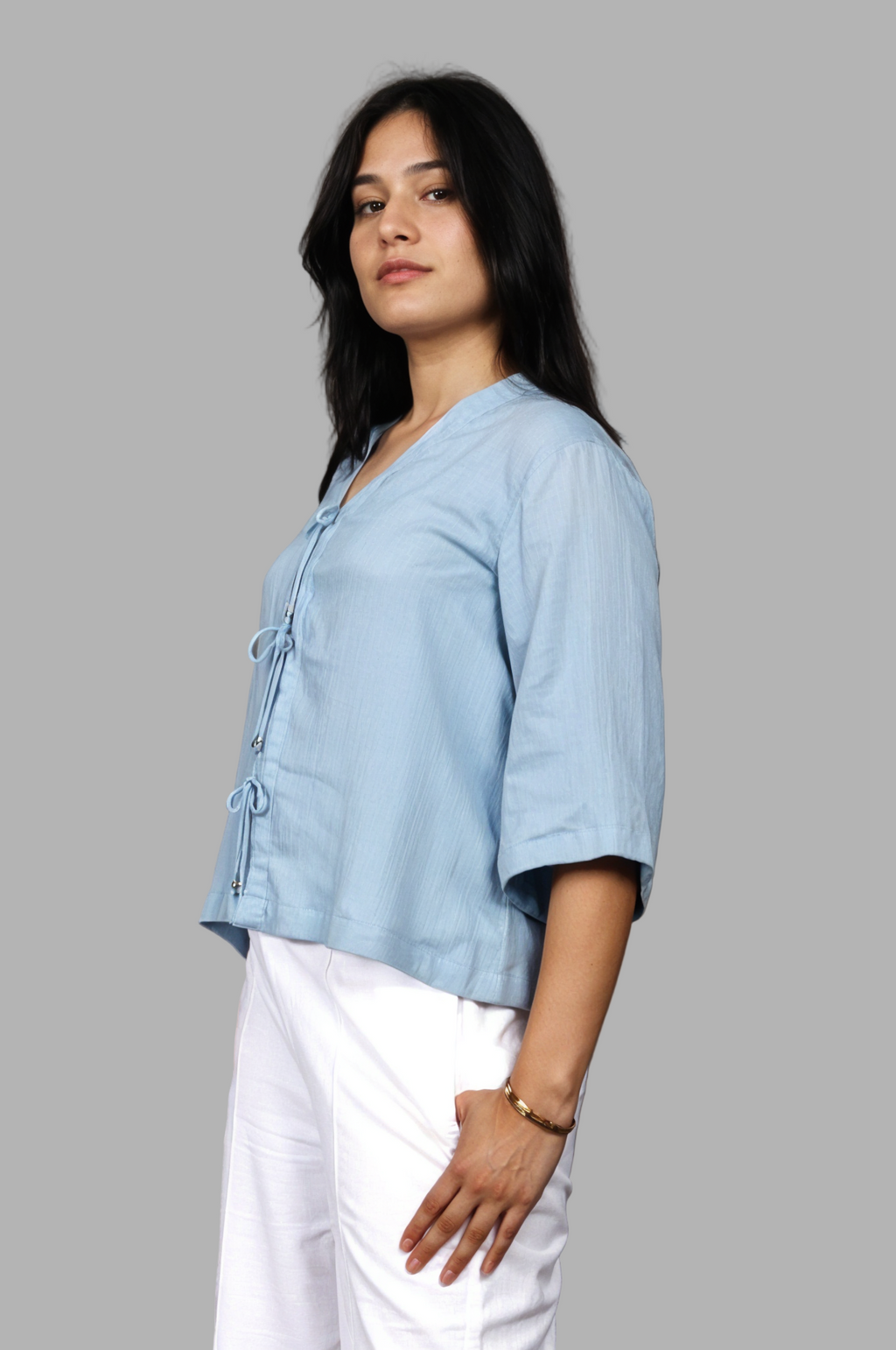 Woman wearing a fullblank branded light blue top called RIVA-B with a plain background