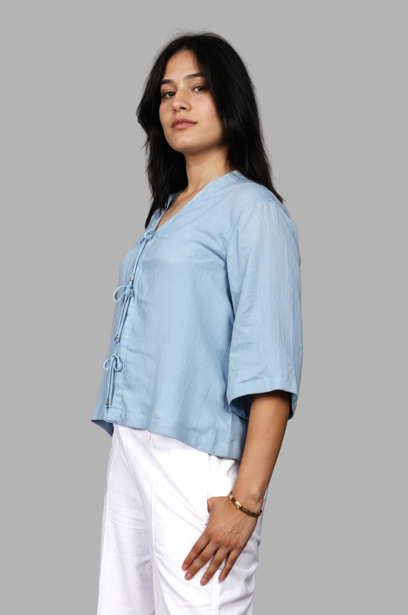 Woman wearing a fullblank branded light blue top called RIVA-B with a plain background