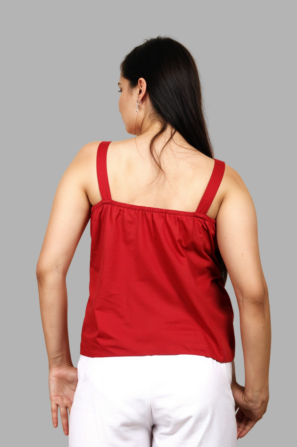 Woman wearing a fullblank branded red top with a bow detail called TWIXY-B with a plain background